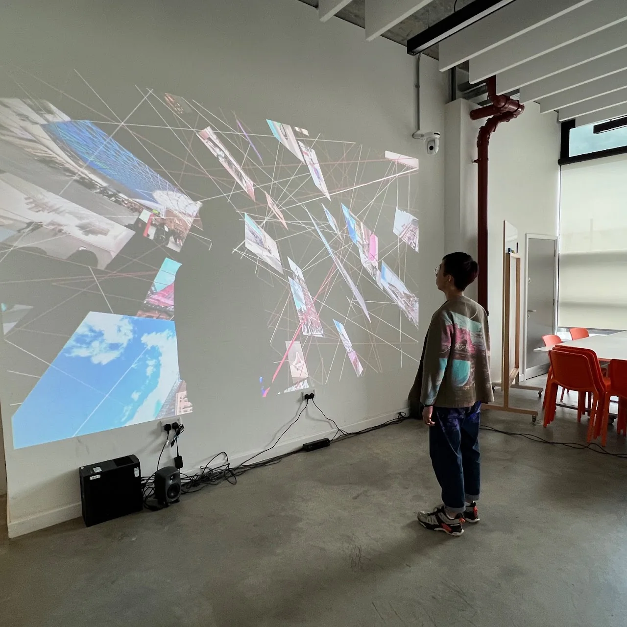 A visitor viewing a projected network of image fragments in an exhibition space.
