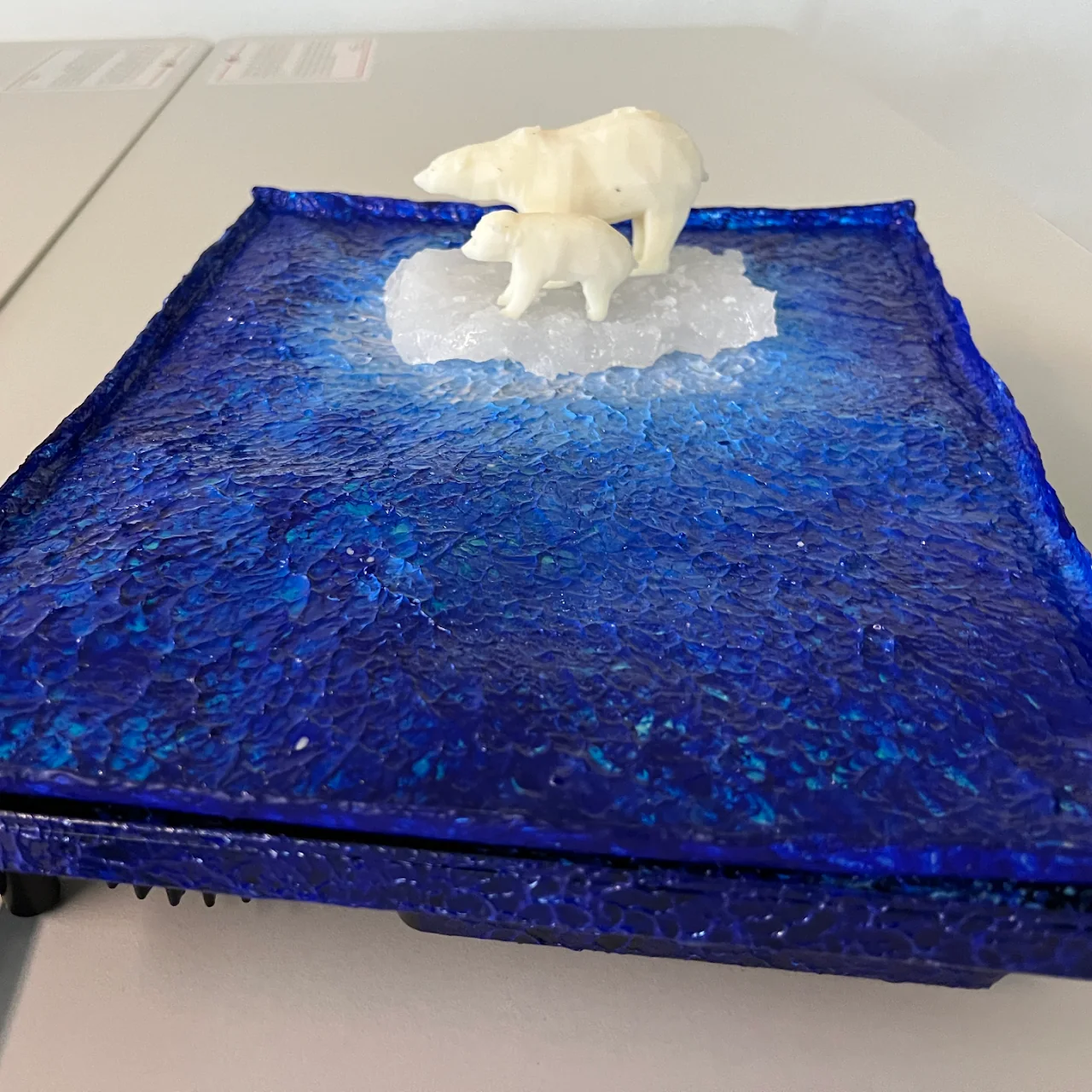 White polar-bear forms resting on a blue melting sculptural surface.